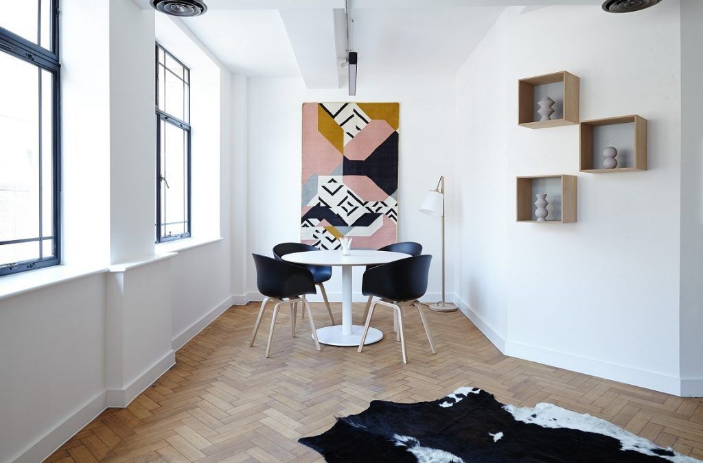 Esszimmer mit weißen Wänden und Holzboden. Runder kleiner Esstisch mit schwarzen Stühlen.